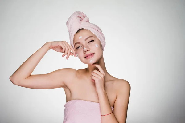 Csinos fiatal lány rózsaszín hc törülközőt a fején helyez arc hidratáló krém — Stock Fotó