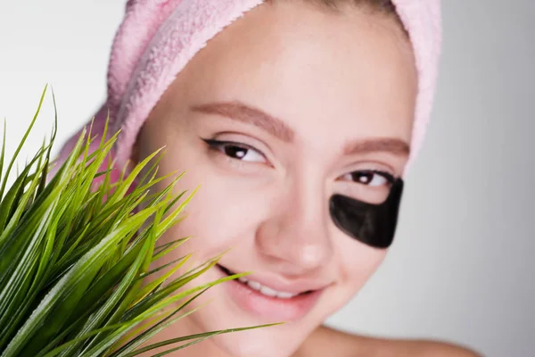 Lachende meisje met een roze handdoek op haar hoofd, onder de ogen zwart patches, schoonheidsinstituut — Stockfoto