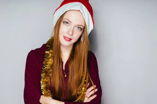Hermosa chica pelirroja en una capucha como Santa Claus celebra el nuevo año 2018 —  Fotos de Stock