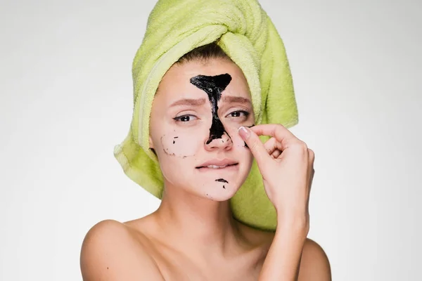 Szomorú, fiatal lány, egy zöld törülközővel a fejét a fekete maszk eltávolítása arcát, ő is kényelmetlen — Stock Fotó