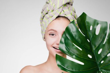 holding bir yaprak yeşil, gün spa başında bir havlu ile sevimli gülümseyen kız