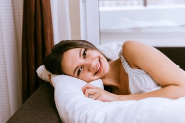 Kız yalan beyaz bir battaniye altında yatakta gülümseyen güzel kalkmak istemiyor