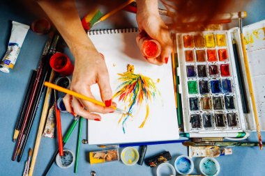 kadın ressam boyalar çok renkli guaj ve fırçalar ile beyaz kağıt üzerinde