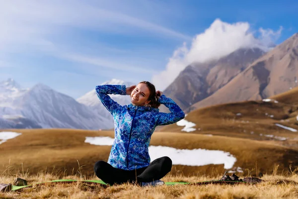 Милая молодая девушка путешествует по Кавказскому хребту, в голубой куртке, наслаждается природой — стоковое фото