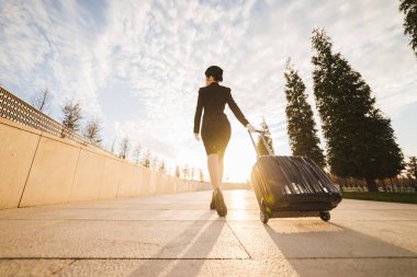 Uçakta hostes formunda ve bir çanta ile ince genç kadın gider