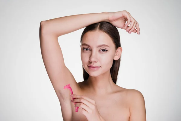 Linda joven se afeita el pelo en sus axilas con una navaja de afeitar rosa —  Fotos de Stock