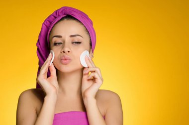 sevimli genç kız başında pembe havlu Pamuk tamponlarla suratla temizler