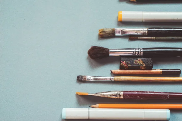 Sobre una mesa azul yacen pinceles de arte y lápices para dibujar —  Fotos de Stock