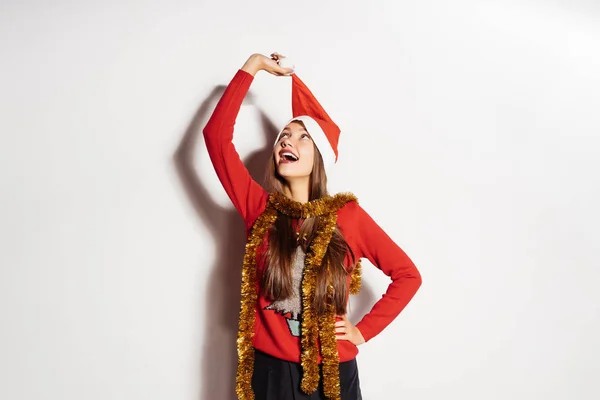 Glückliches junges Mädchen nimmt eine rote Mütze wie der Weihnachtsmann vom Kopf und wartet auf ein neues Jahr und Weihnachten — Stockfoto