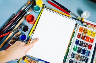 bir mavi beyaz bir defter, parlak suluboya renkler ve guaj tablodur