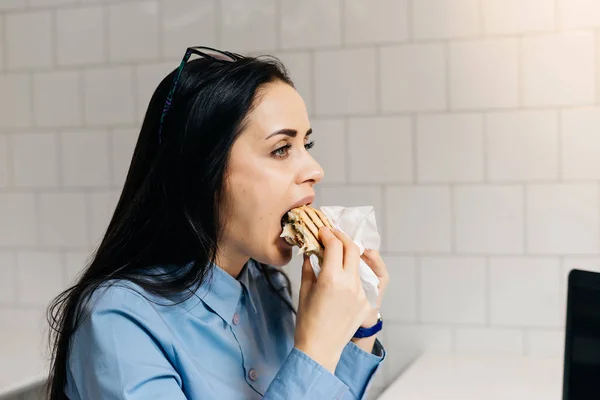 空腹の少女は熱心にカフェでサンドイッチを食べる — ストック写真