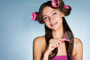 sevimli gülümseyen kız bir tarak ve curlers ile şık bir saç modeli yapmak