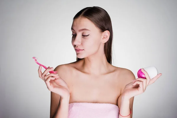 Linda menina detém um desodorizante aromático e uma navalha rosa — Fotografia de Stock