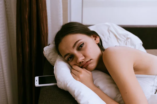 眠そうな少女の白い毛布の下のベッドに寝て、起きたくないです。 — ストック写真
