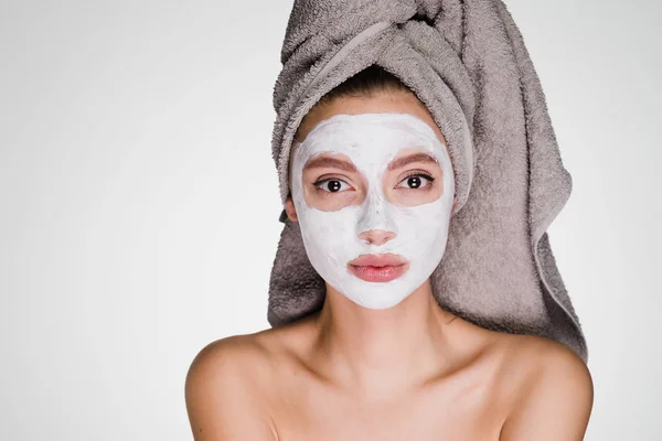 Atraktivní dívka s ručníkem na hlavě použita bílá hydratační maska na obličej — Stock fotografie