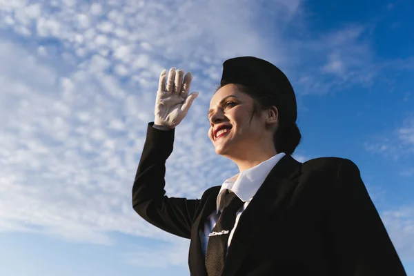 Счастливая молодая стюардесса в форме думает о полете, под голубым небом — стоковое фото