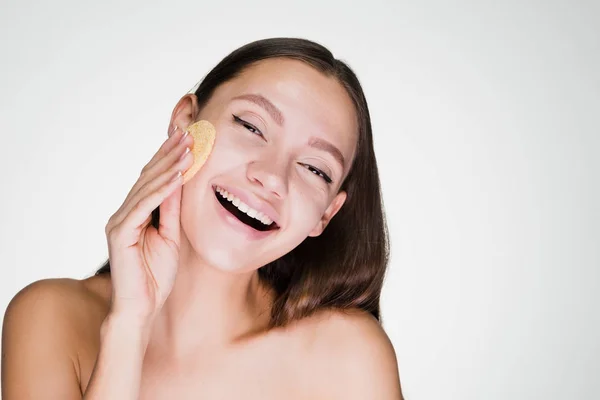 Menina sorridente feliz limpa a pele com uma esponja — Fotografia de Stock