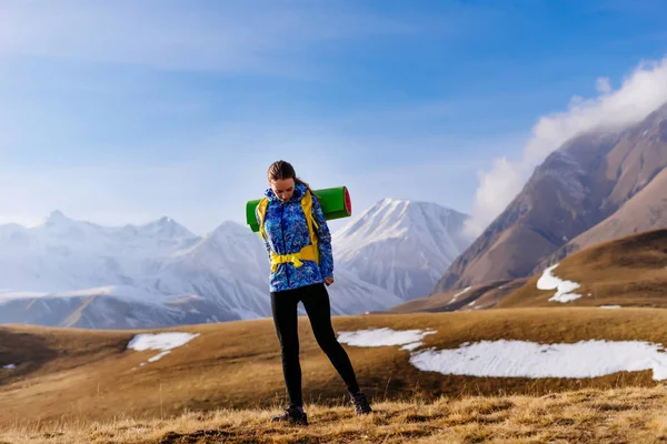 Активная молодая девушка в синей куртке путешествует по Кавказскому хребту с рюкзаком — стоковое фото