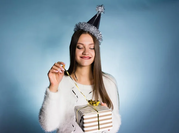 Счастливая молодая девушка в шапке на голове получила подарок на новый год, открывает коробку — стоковое фото