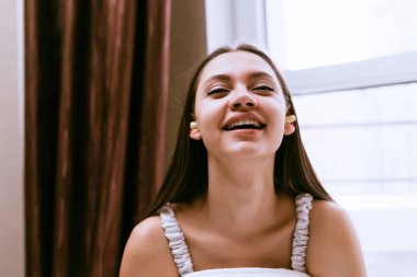 mutlu genç kız yatakta oturur, o bir izinli