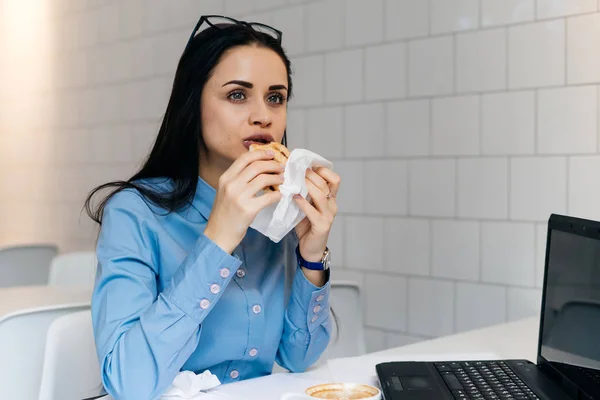 Hladová dívka student v modré košili na večeři v café po přednáškách na univerzitě — Stock fotografie
