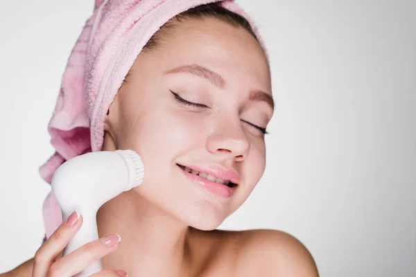 Cute happy girl doing deep cleansing of face skin with electric brush, eyes closed — Stock Photo, Image