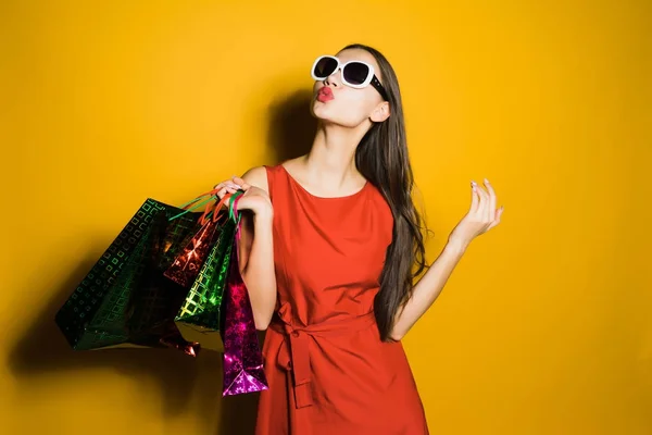 Menina feliz em um vestido vermelho e óculos de sol, comprei muitos presentes em uma sexta-feira preta — Fotografia de Stock