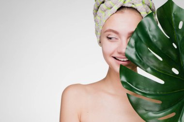 mutlu genç kız başında bir havlu ile yaprak yeşil, güzellik hakkında düşünüyor tutar