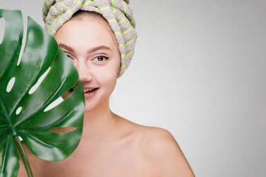 holding bir yaprak yeşil, gün spa başında bir havlu ile sevimli gülümseyen kız