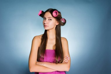 Kendine güvenen genç kız güzellik hakkında onun kafa büyük pembe saç curlers düşünüyor.