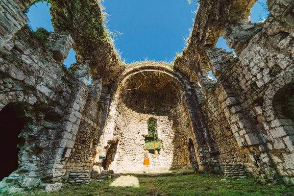 Het meisje is reizen, permanent in een eeuwenoude verwoeste gebouw omgeven door groen — Stockfoto