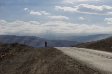 Orada yolda doğa ilham verici dağlar ve gökyüzü arka planı bir adamdır