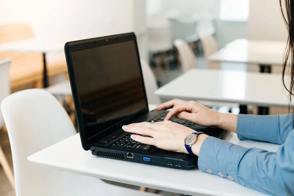 Девушка фрилансер в синей рубашке работает на ноутбуке — стоковое фото