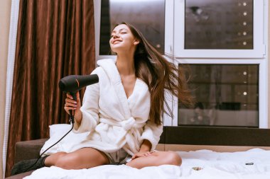 sevimli genç uzun saçlı kız yatakta oturur onun saç kurur