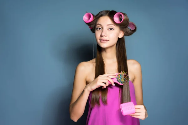 くしや髪のカーラーで髪を束ねているかわいい若い女の子 — ストック写真