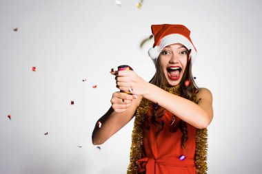 başında kırmızı bere ile mutlu genç kız bir yılbaşı kraker patlar, kutluyor