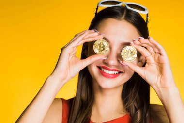 Altın bitcoins gözlerle tutan güzel gülümseyen kız