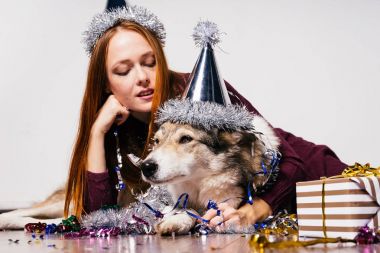 Festival şapkalı güzel kızıl saçlı kız yere köpeğiyle, yeni yıl için bekleyen oturuyor