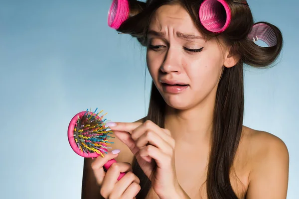 Грустная молодая девушка теряет волосы, на голове большие розовые бигуди — стоковое фото