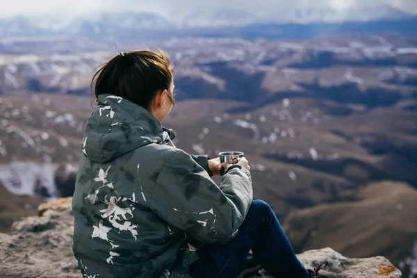 A lány utazik, ül a szélén a szikla, italok, forró tea, és élvezi természet — Stock Fotó