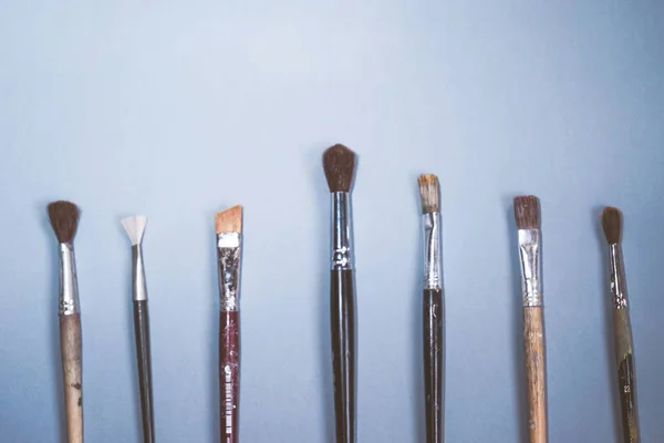 Mavi bir masada sanatsal fırçaların farklı boyutlarda vardır — Stok fotoğraf