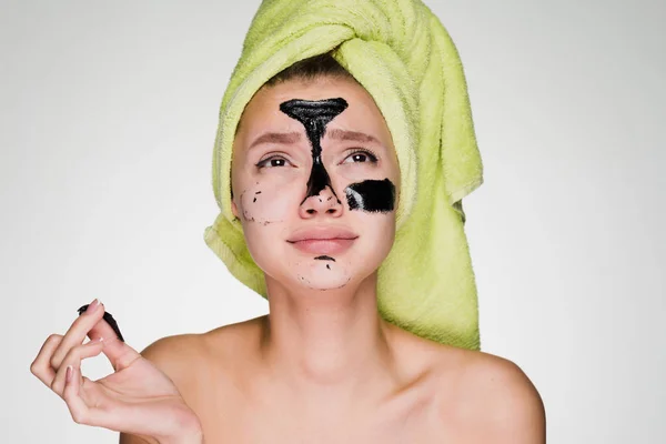 Sad young girl with a green towel on her head removes the black mask from her face — Stock Photo, Image