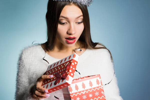 A young girl received a gift for the new year and looks surprised — Stock Photo, Image