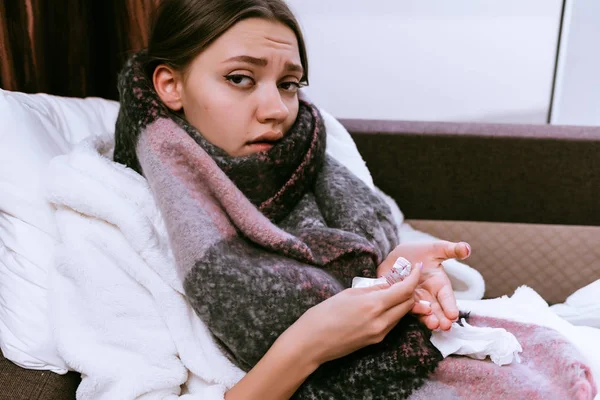 Больная девушка в теплом шарфе пьет лекарства — стоковое фото