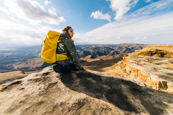 Žena turistické velký žlutý batoh sedí na pozadí hor — Stock fotografie