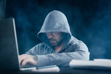 bir adam hacker bir dizüstü oturur ve bir şey basar