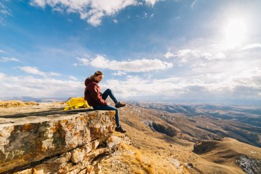 kadın turist dağ kenarında güneşli bir günde oturur.