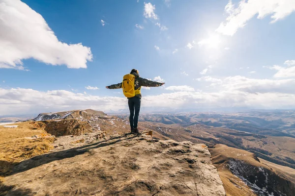 Turista mulher com uma grande mochila de pé no fundo das montanhas — Fotografia de Stock