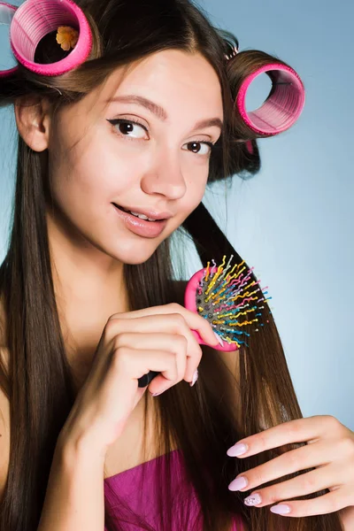 Una donna con i bigodini sui capelli si pettina i capelli — Foto Stock