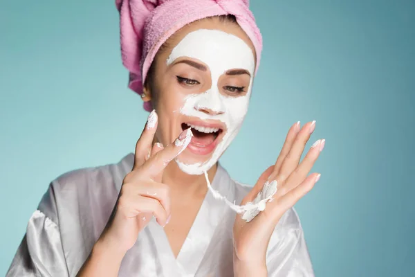 Boldog asszony, a fejét egy törülközővel alkalmazni a fehér maszk a bőr az arcán — Stock Fotó